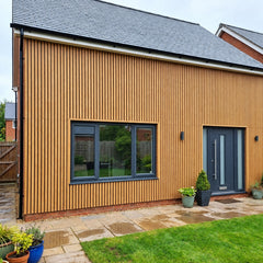 Light Oak WPC wall panels installed on the exterior of a house, slatted wood effect finish, 15×240cm, 12mm thick, Solid Furniture UK