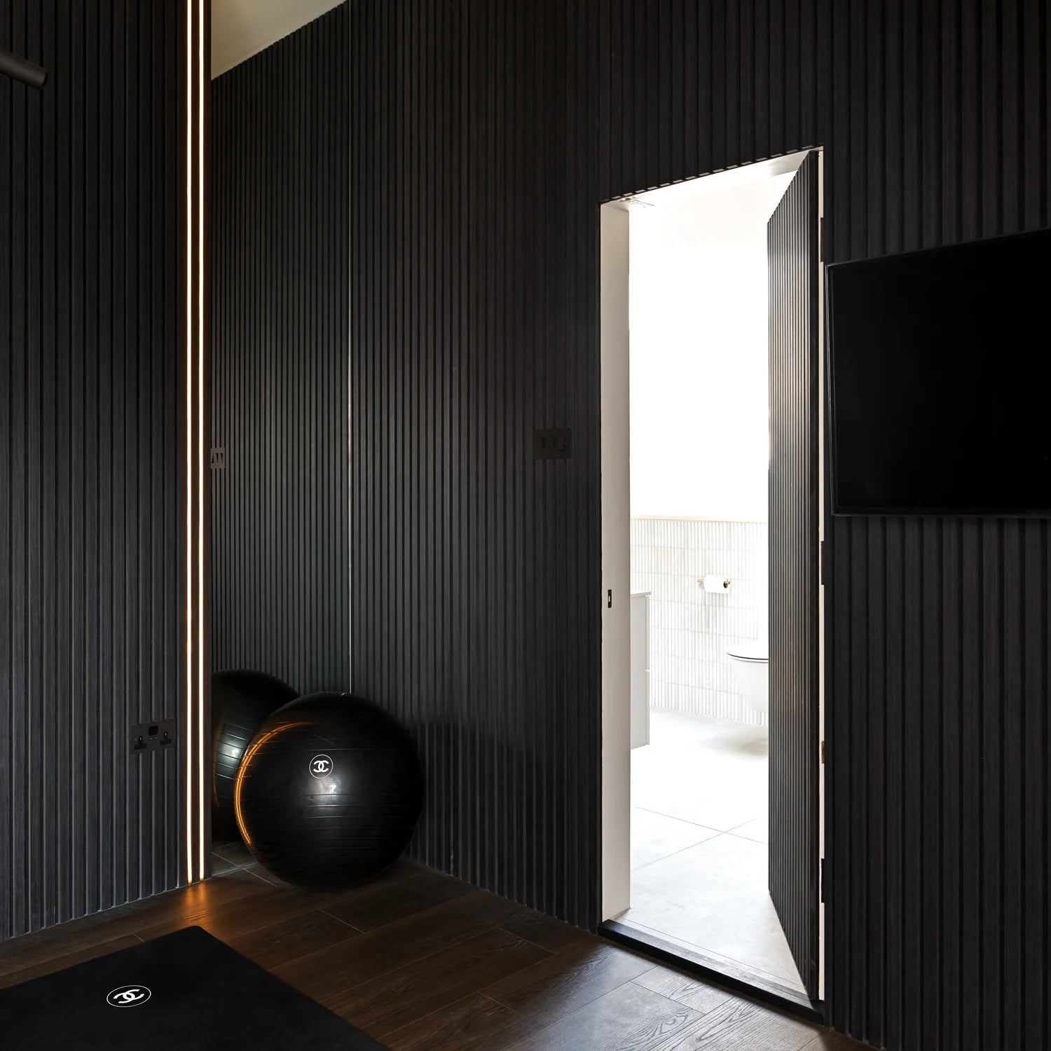 Modern room interior in the UK featuring black HDF acoustic slatted wall panels 60x240cm by Solid Furniture UK for improved acoustics and sleek design.