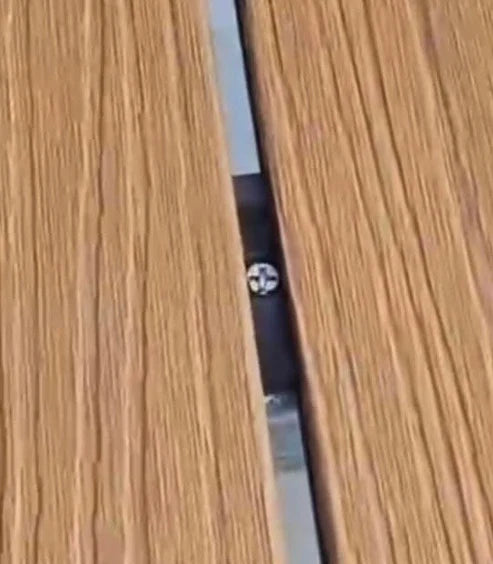 Decking fittings being placed into grooves of composite decking boards during installation process. Solid Furniture UK