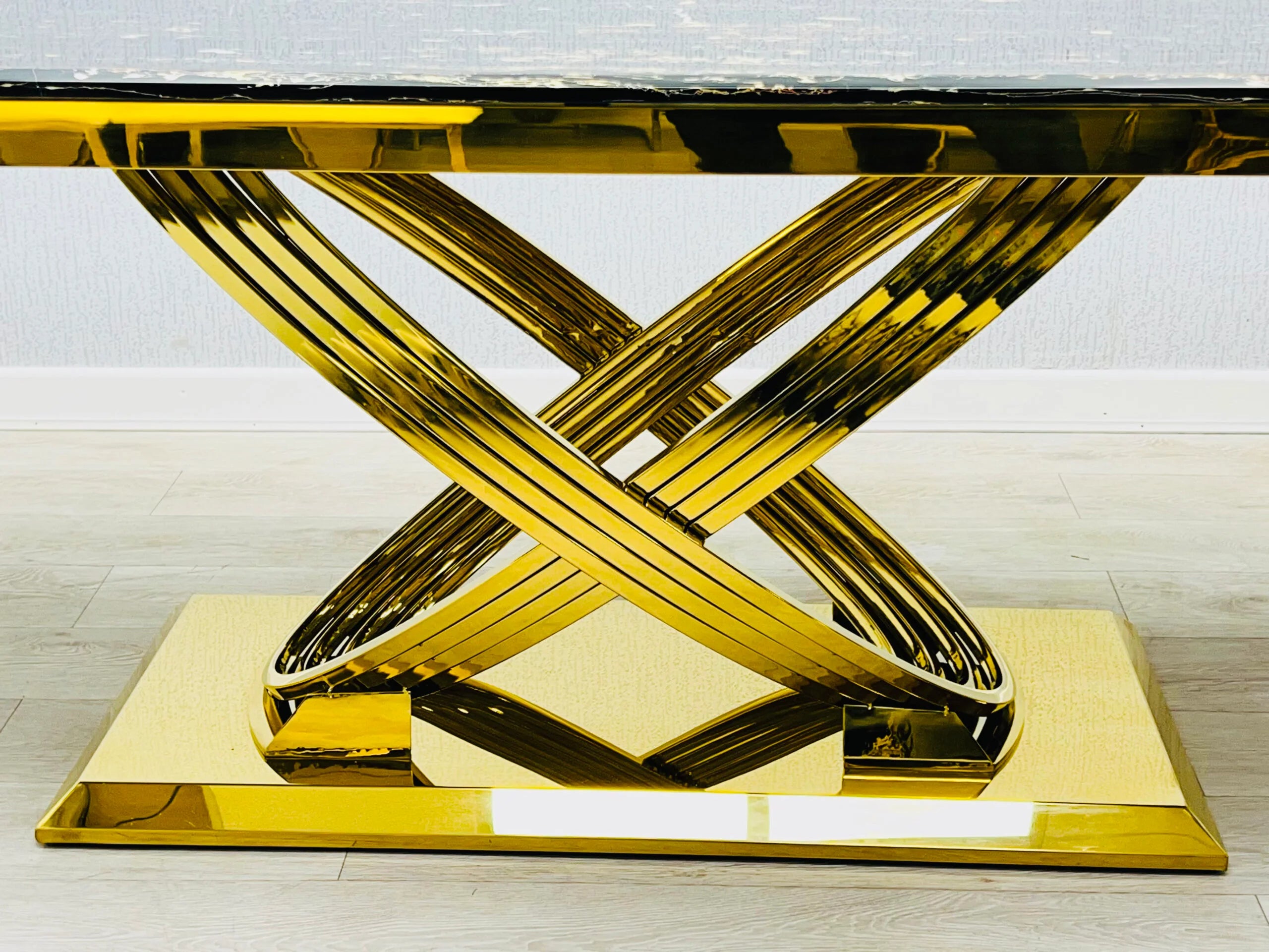 Close-up view of Elina black and gold marble dining table highlighting the elegant gold-coated metal base with a strong and modern luxury finish. solid furniture UK