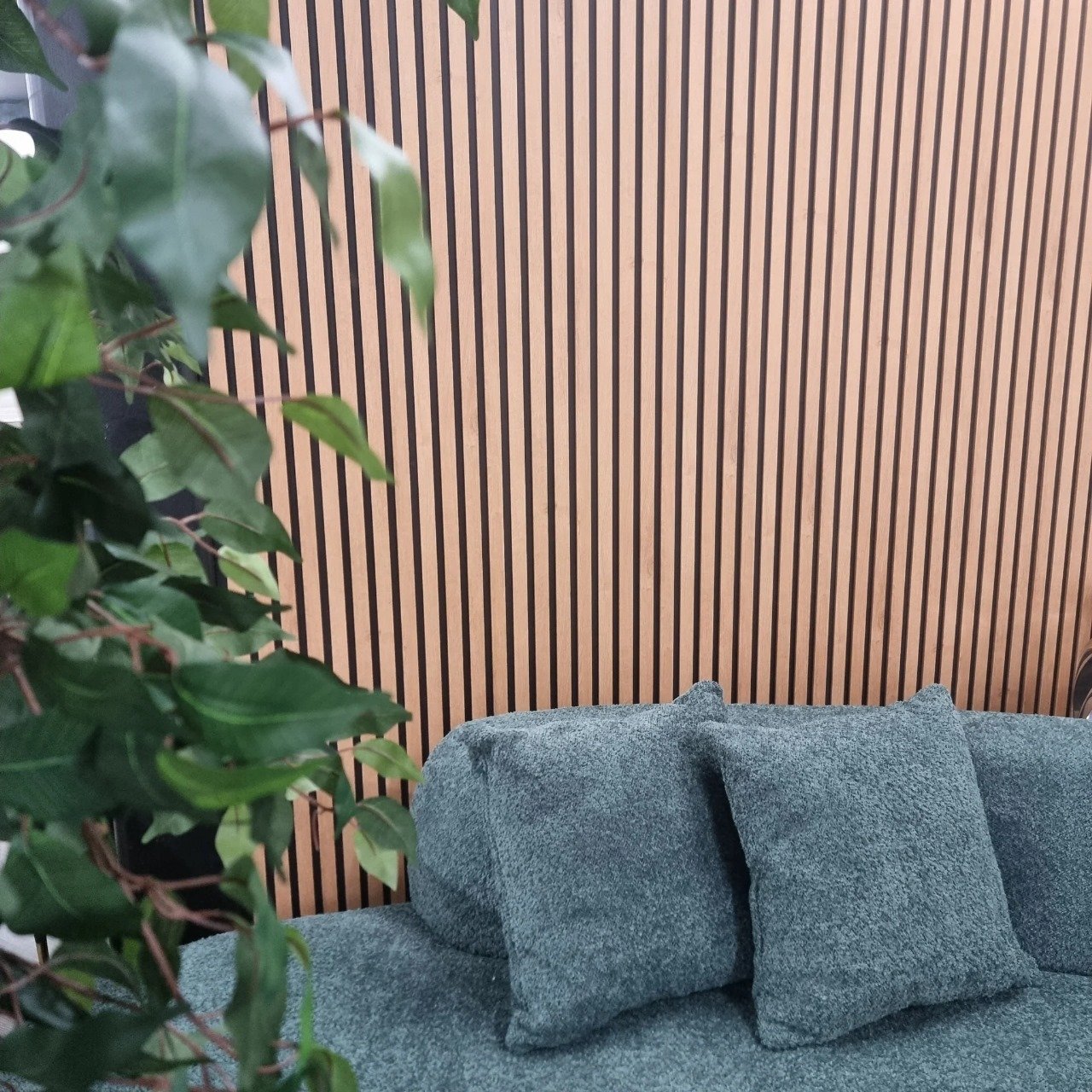 Light Oak WPC wall panels installed in a living room from a different angle, showing the slatted wood effect finish, Solid Furniture UK