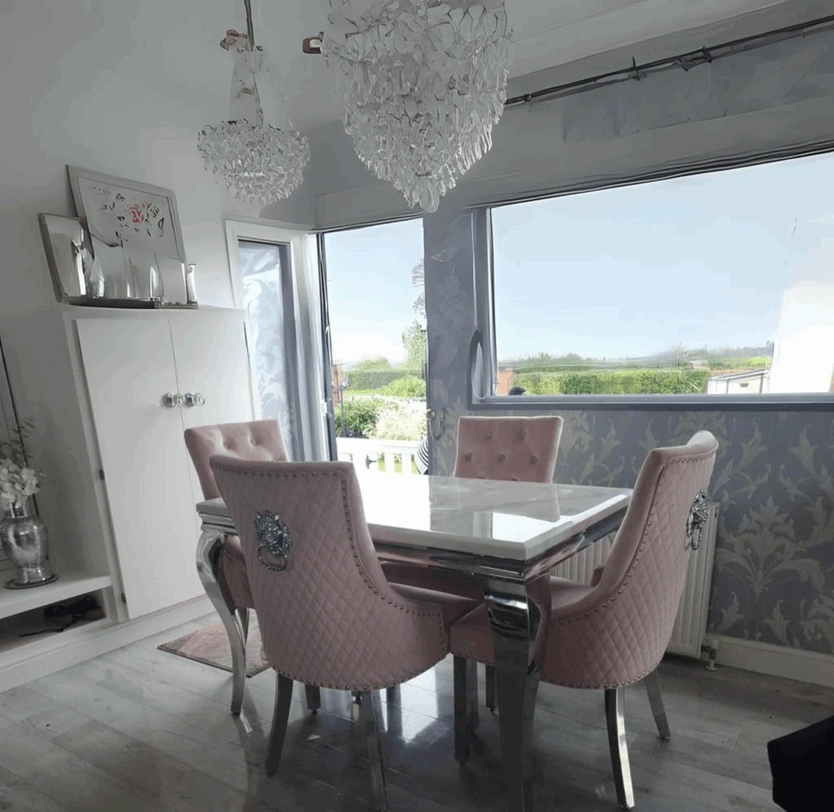 Side angle view of Louis white marble dining table with pink Majestic velvet dining chairs from Solid Furniture UK