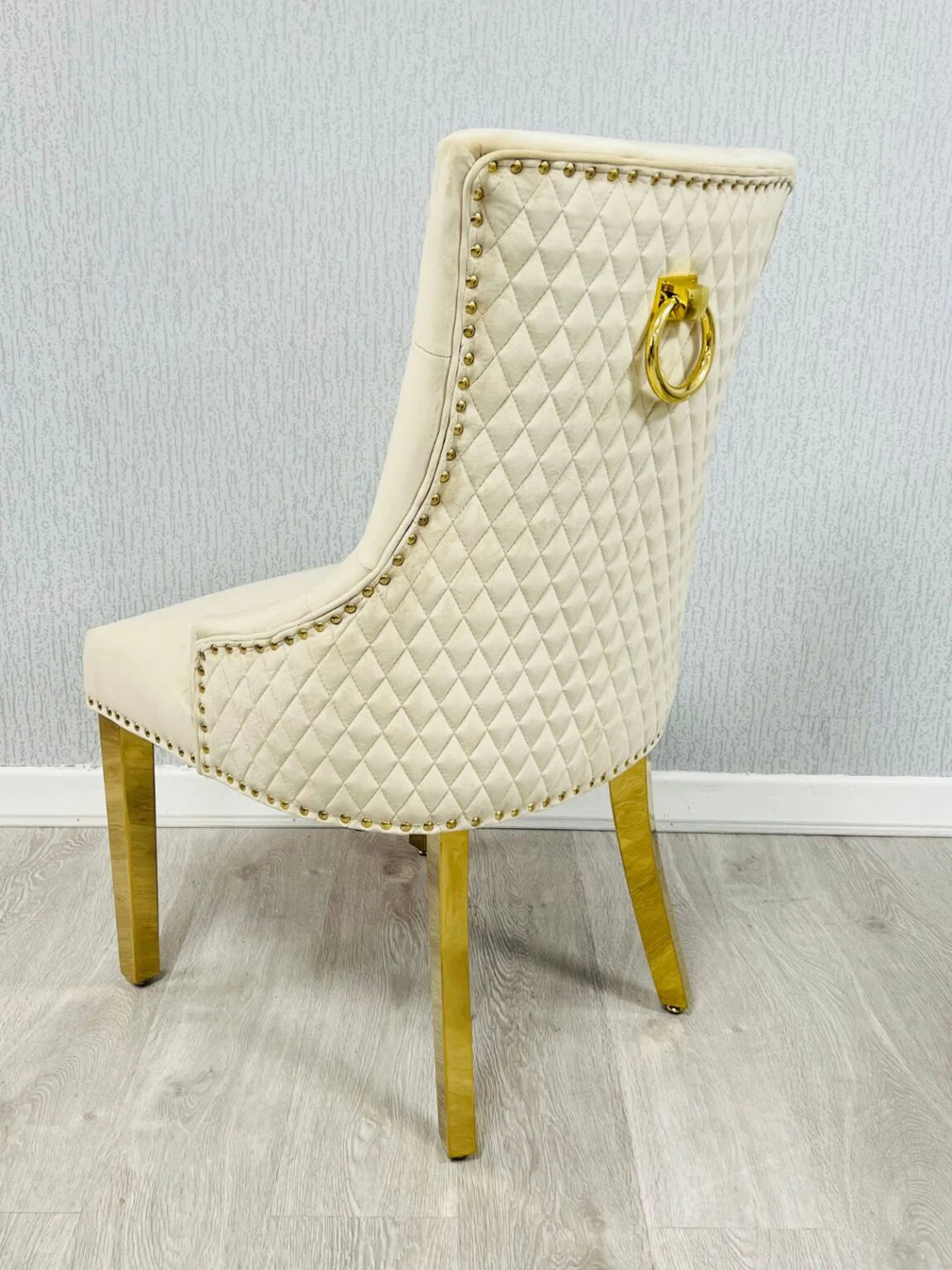 Angled view of Majestic Mink Gold upholstered dining chair showing elegant gold detailing from Solid Furniture UK