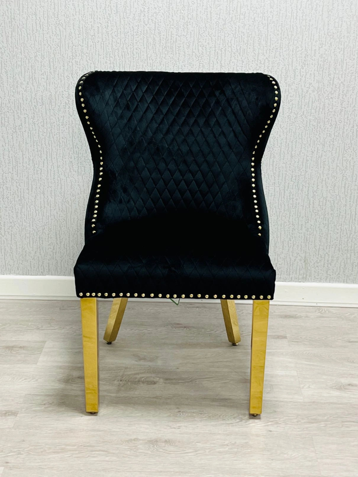 Main front view of Valentino black velvet dining chair featuring ring knocker detail, gold-finished legs and luxury upholstered design by solid furniture uk