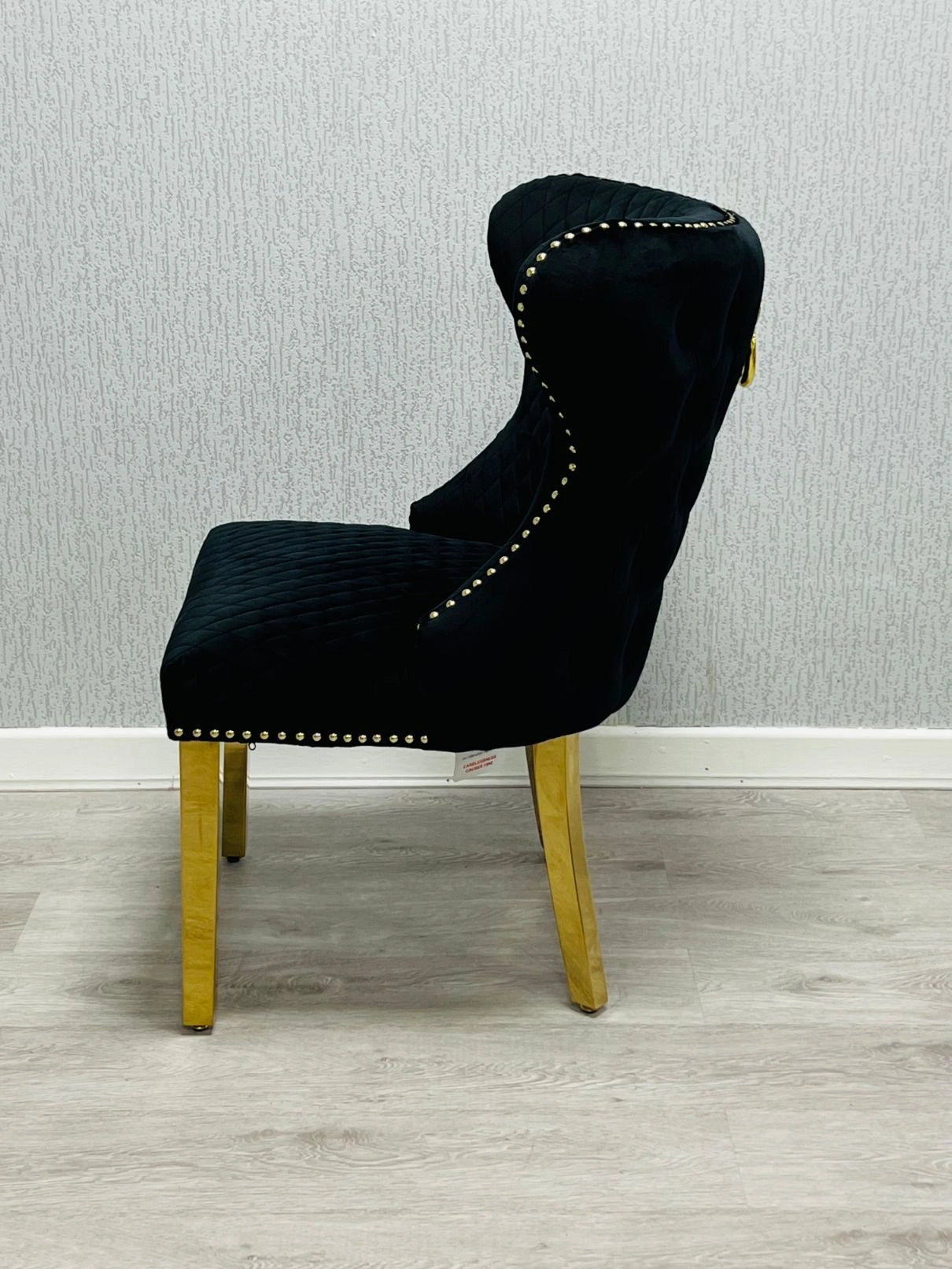 Side view of Valentino black velvet dining chair featuring ring knocker detail, gold-finished legs and luxury upholstered design by solid furniture uk