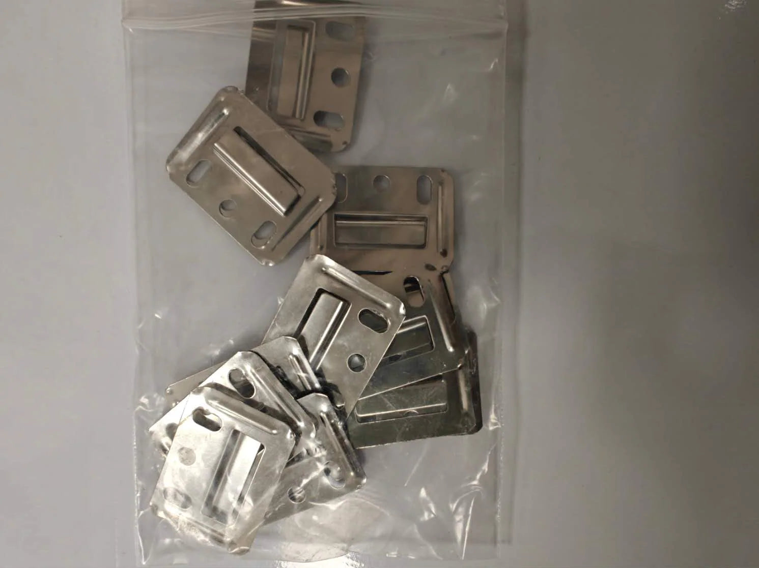 Pack of 100 WPC wall panel brackets from Solid Furniture UK neatly arranged for bulk interior wall panel installation projects